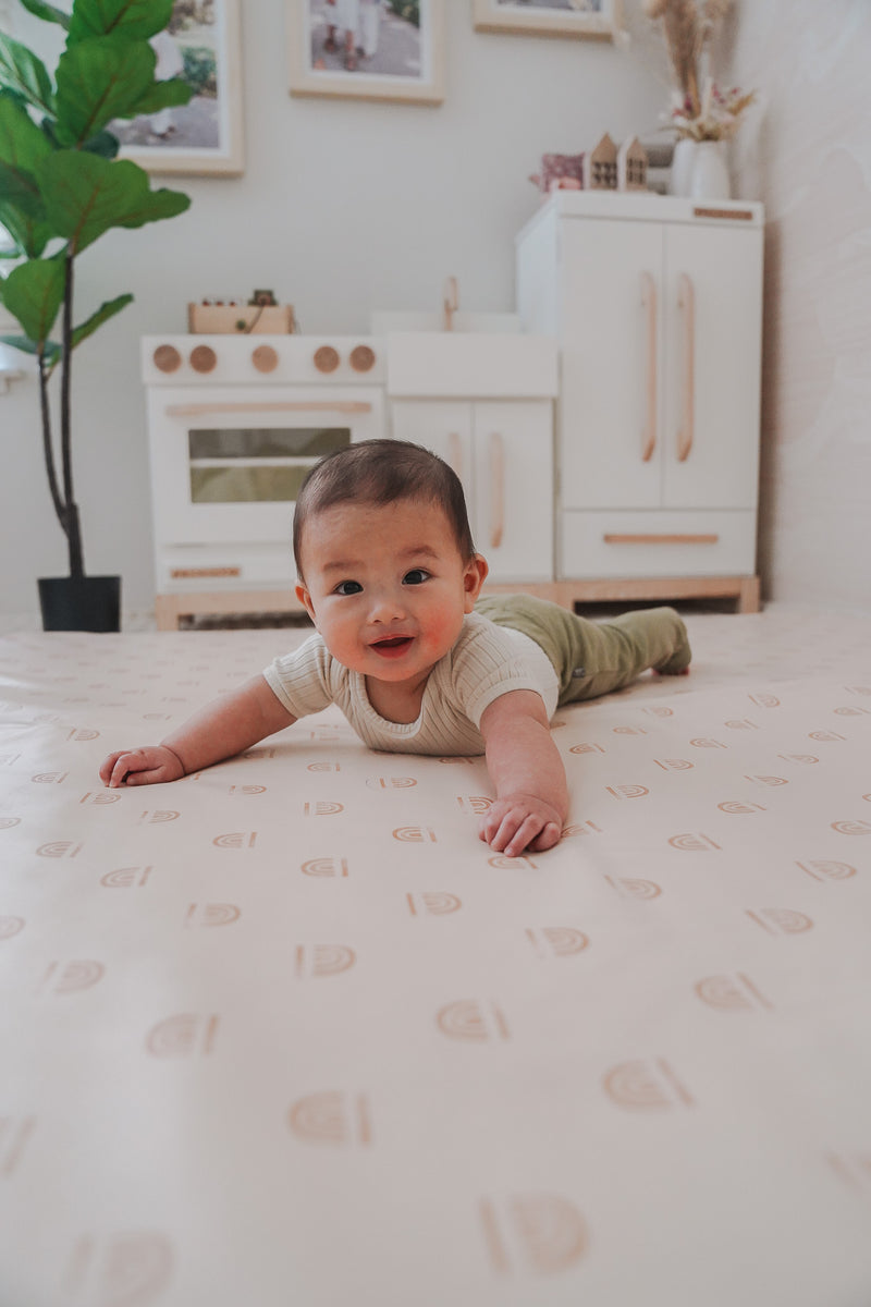 baby laying stomach down on play mat, smiling