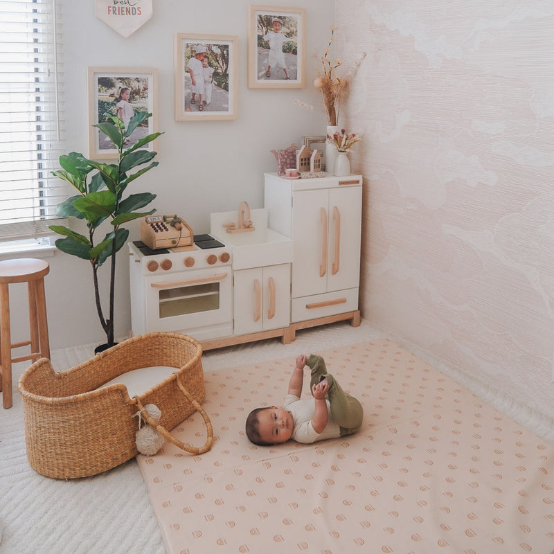 Baby laying stomach up on play mat, holding their feet