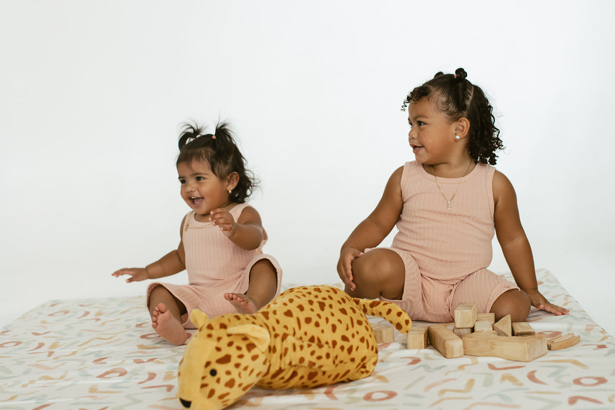 two children playing on a toki mats play mat in the print Pastel Party