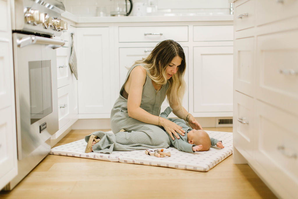 eli yonas, founder of toki mats, playing with her baby on a toki mats play mat