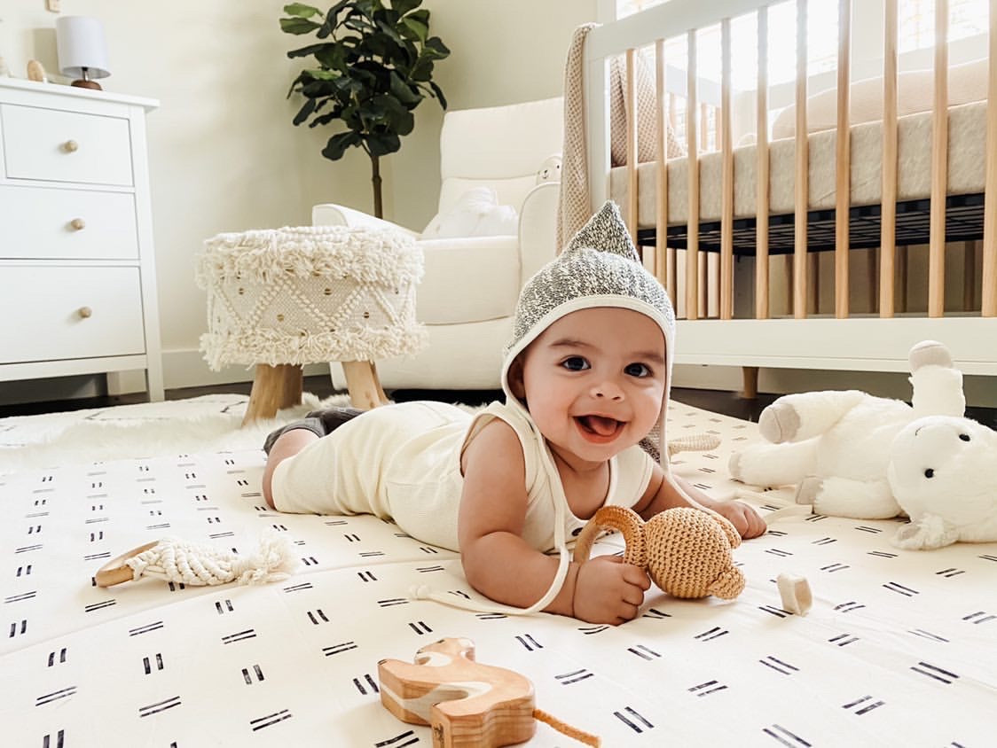 baby laying on a toki mat on the floor of a nursery