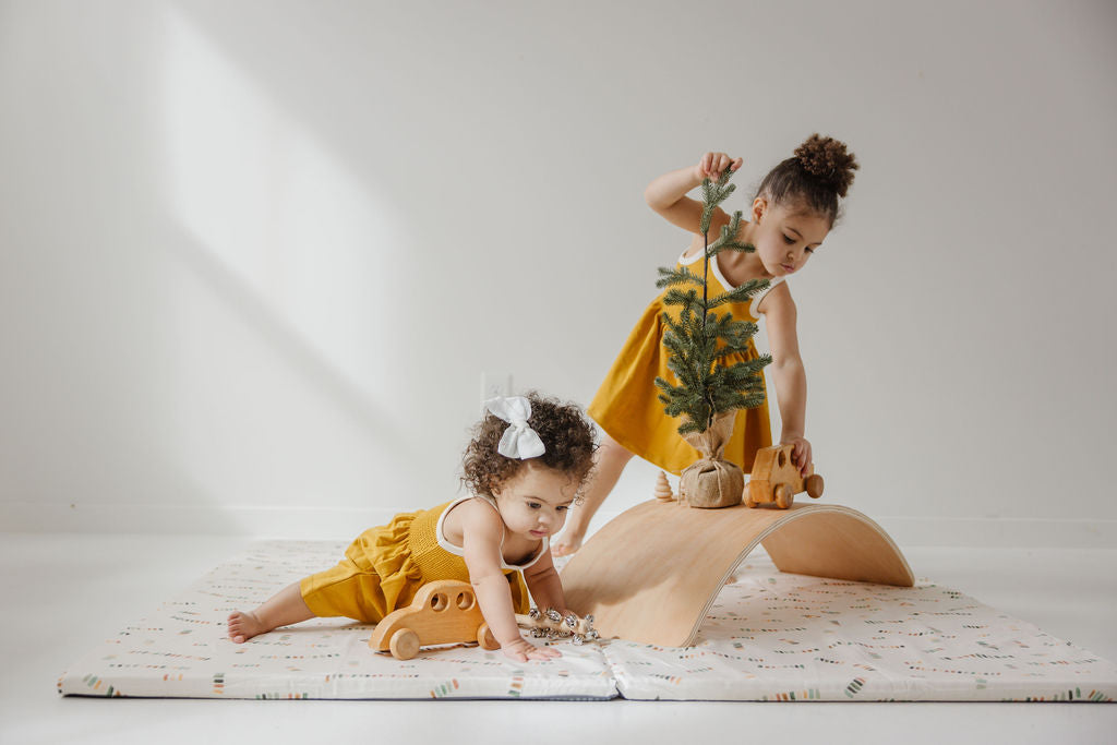 kids playing on a toki  mats play mat with a small fir tree