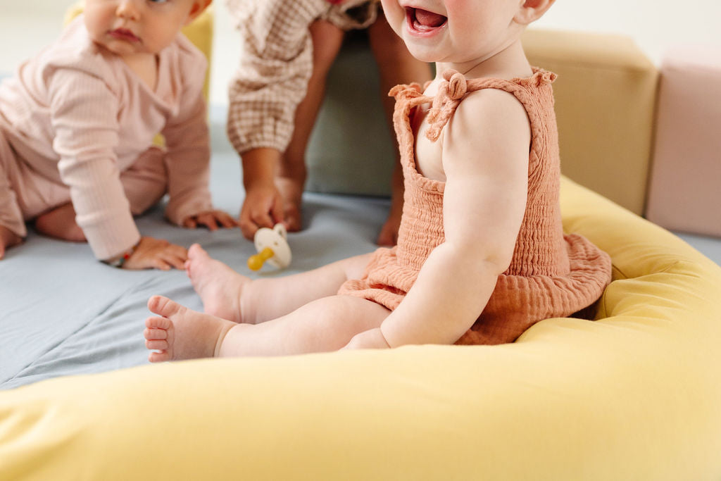 baby sitting up with a toki mats support pillow