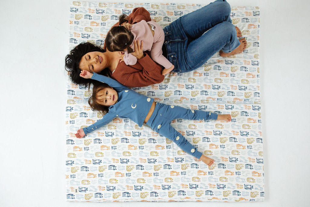 mom playing with two kids on a toki mats play mat
