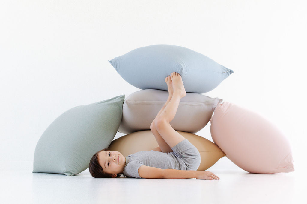 child laying in front of stacked toki mats bean bags