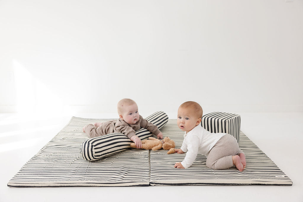two babies laying on a toki mats play mat