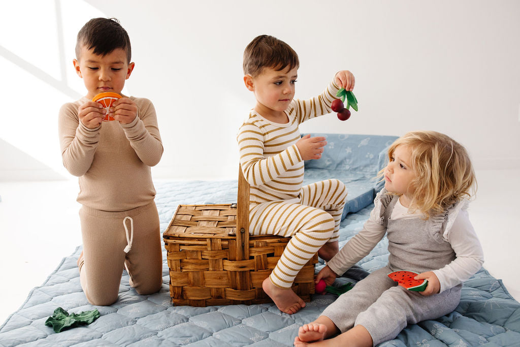 three toddlers sitting on a toki mats picnic blanket