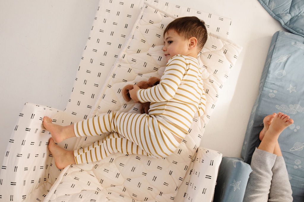 toddler laying on a toki mats play couch