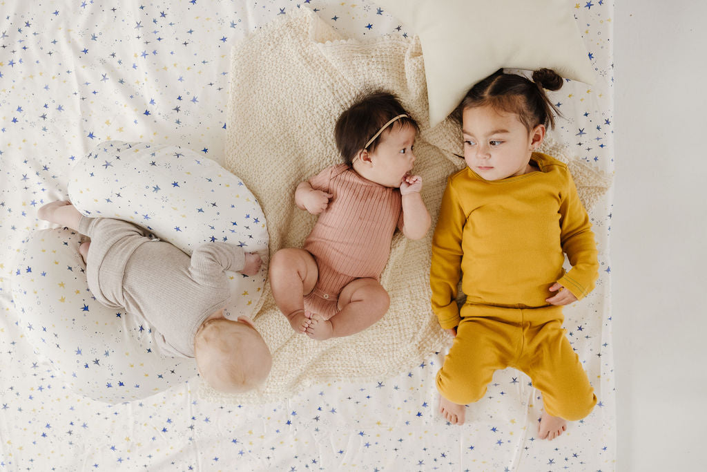 baby and toddler laying on a toki mats play mat