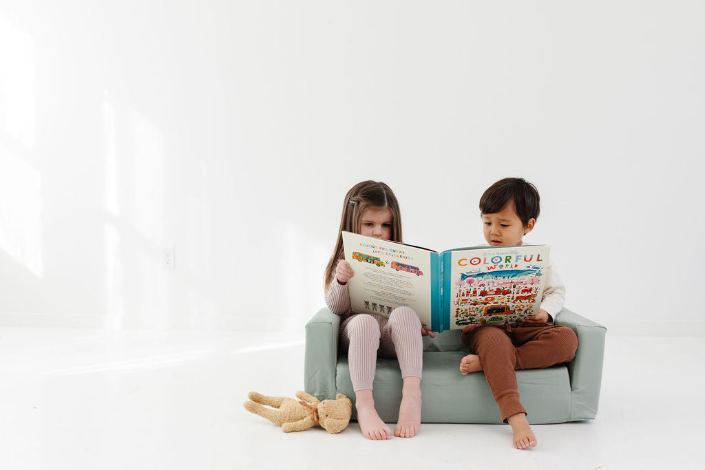 two children reading books on a toki mat play couch