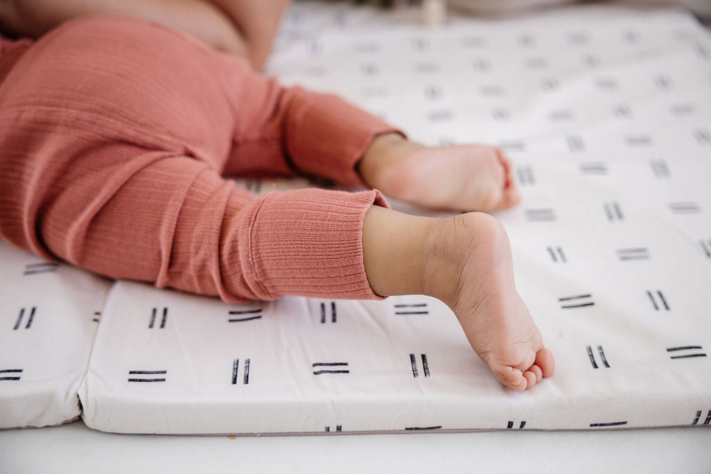 baby laying on their stomach on a toki mats play mat