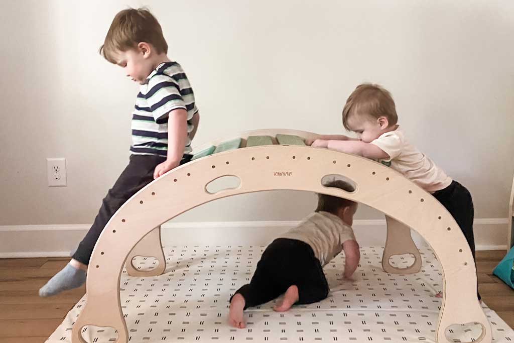tara dion's sons playing on a wooden arch and toki mat